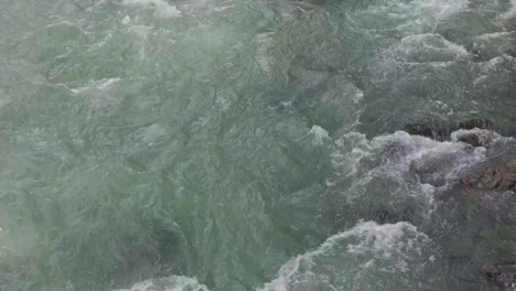 strong current flowing in shallow river with greenish water