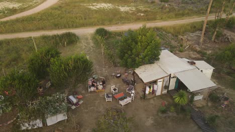 antena dando vueltas sobre personas relajándose en el jardín de una casa prefabricada al atardecer, punta del diablo en uruguay