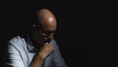 depressed mature man struggling with mental health sitting in darkness on sofa with low key lighting 5