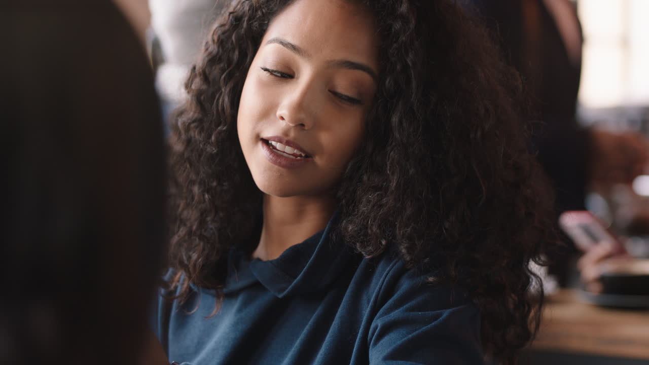 hermosa adolescente usando un teléfono inteligente hablando con una amiga en un café socializando disfrutando de la conversación pasando el rato en una cafetería ocupada