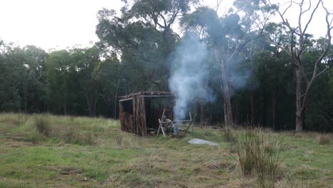 Ein-Buschmann-Macht-Ein-Lagerfeuer-In-Einem-Baumrindenstall-Im-Australischen-Busch