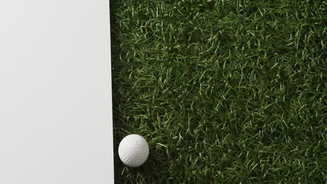 Primer-Plano-De-Una-Pelota-De-Golf-Sobre-Césped-Con-Fondo-Blanco,-Espacio-Para-Copiar,-Cámara-Lenta