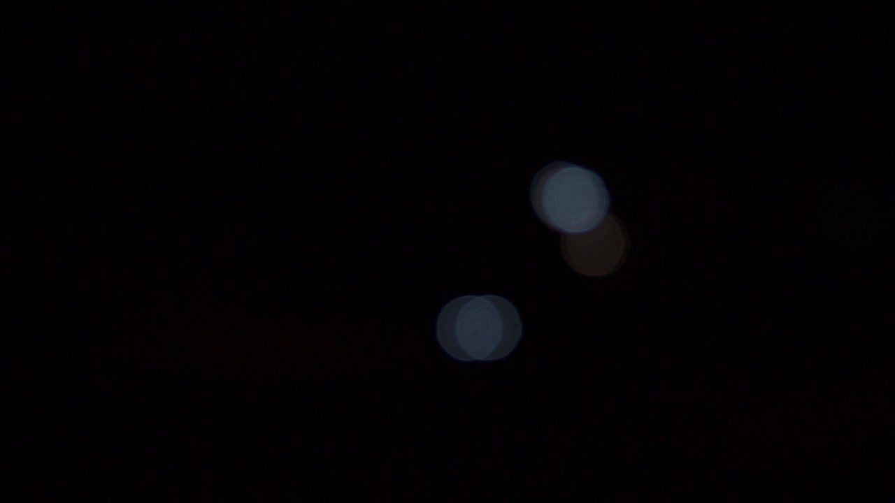 faros de coche fuera de foco, bolas de bokeh en movimiento, noche