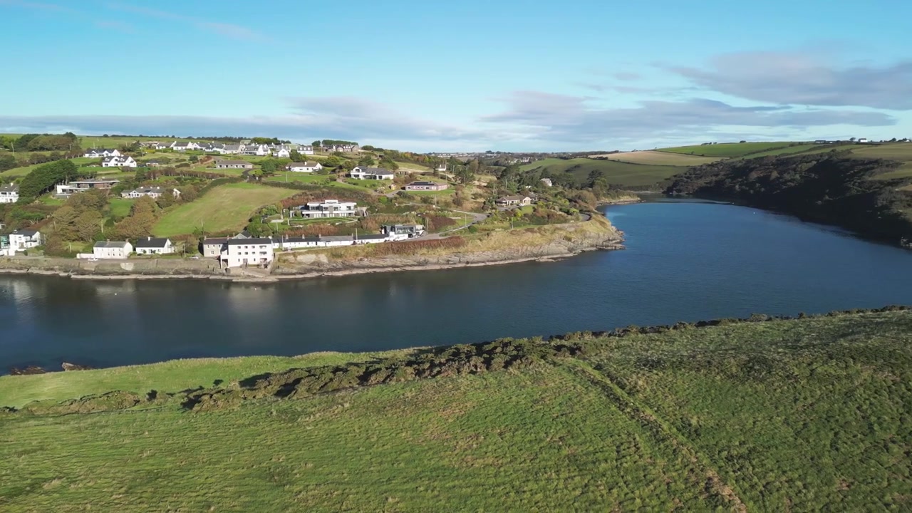 Colline soleggiate e case sparse su di esse, una vista aerea su una baia riparata e una costa rocciosa, Sandycove Kinsale, West Cork Irlanda