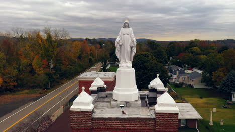 Una-Vista-Aérea-De-Una-Estatua-De-La-Virgen-María-En-La-Parte-Superior-De-Una-Iglesia-Católica-En-El-Norte-Del-Estado,-Ny