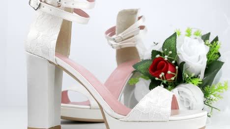 elegant luxury laced bridal wedding shoes and bouquet with red rose on white background closeup