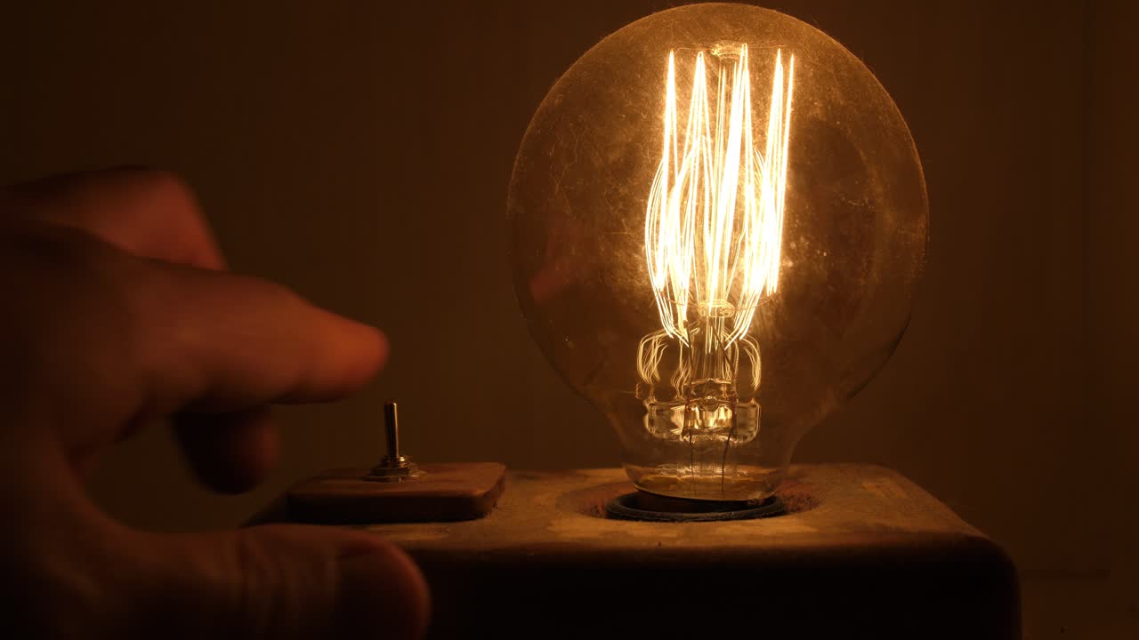 Mano che Spegne una Lampadina Edison Vintage