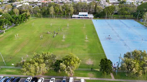 drone captures netball courts and fields at gold coast sporting complex. bright daylight, vibrant greenery, and active sports scene