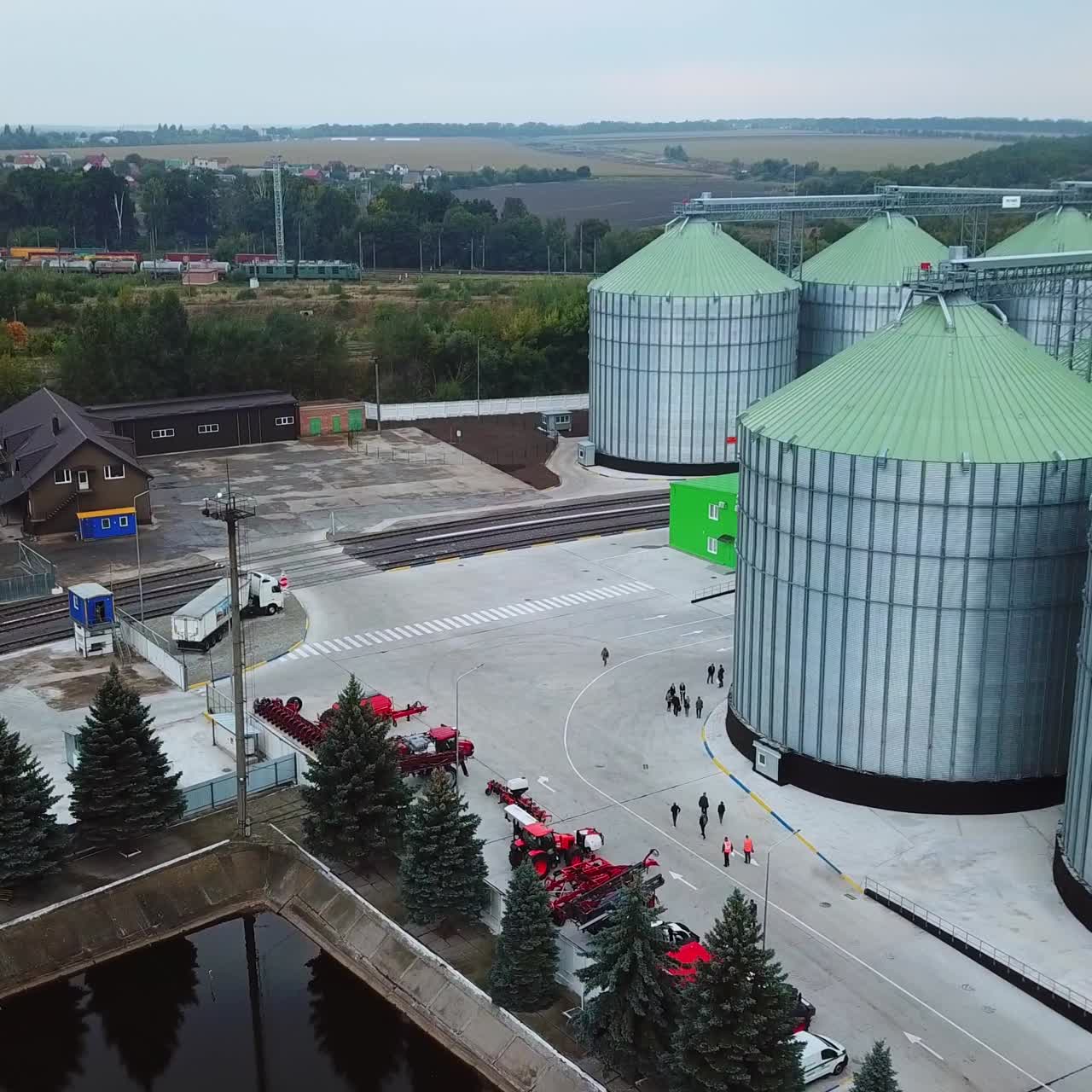 Flying above the modern elevator plant territory. Car park, artificial pond and railways locating at the industrial zone