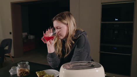 mujer bebiendo jugo en la cocina