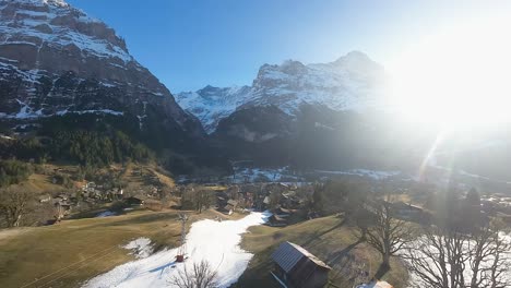 la brillante luz del sol brilla en el pueblo de grindelwald sobre las lejanas cumbres de los alpes.