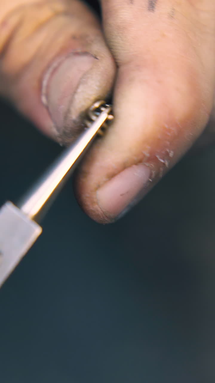 CU: professional jeweler connects little gold links to chain with pliers at workplace in light craft workshop close view