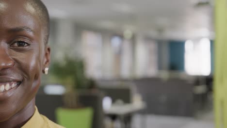 Half-portrait-of-happy-african-american-businesswoman-in-office,-smiling,,-slow-motion,-copy-space