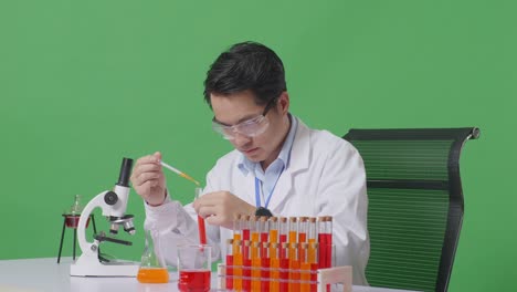 side view of asian man scientist making experiment with test tube and saying wow while working on the table with microscope in the green screen background laboratory