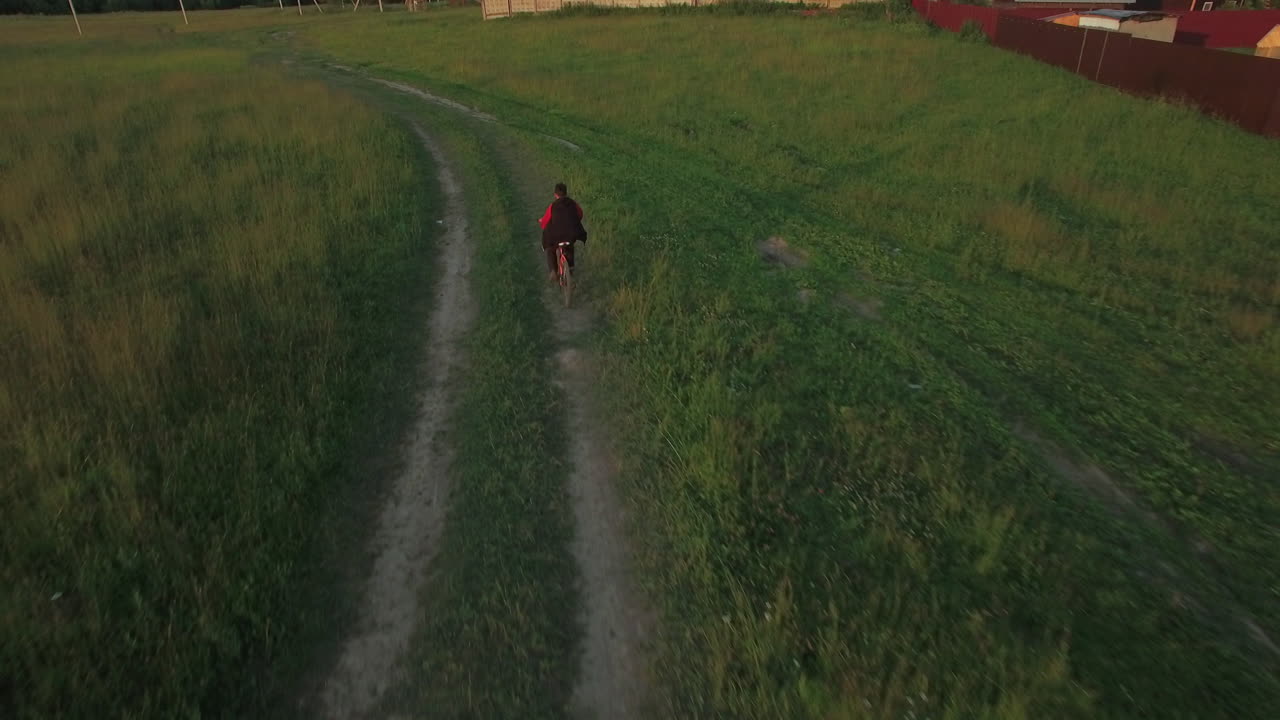 Aerial steadicam view of boy riding a bike at summer Russia