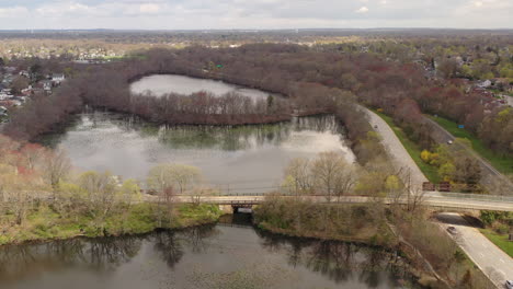 una vista de drones sobre un lago tranquilo, rodeado de árboles secos y caminos pavimentados