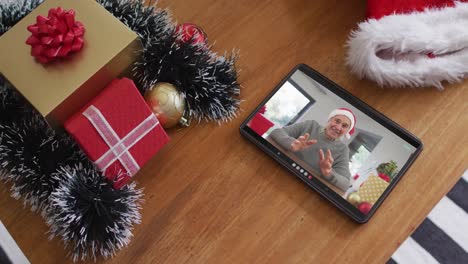Lächelnder-Kaukasischer-Mann-Mit-Weihnachtsmütze-Beim-Weihnachtsvideoanruf-Auf-Dem-Tablet