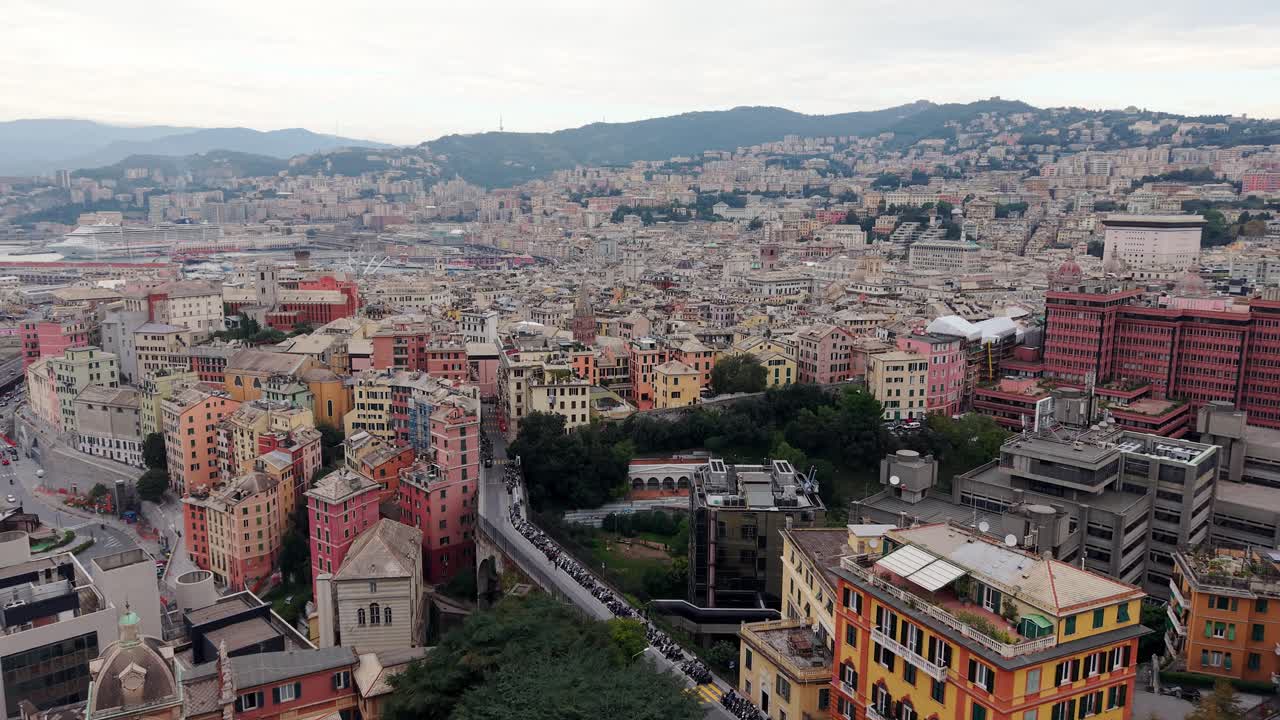 The cityscape of genoa with colorful buildings and hilly terrain in the background, aerial view