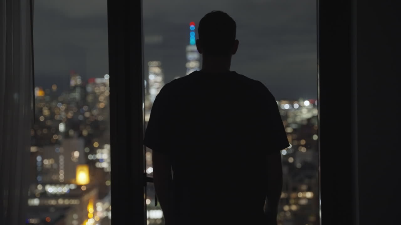 Silhouette of a Man Looking at the New York City Skyline at Night