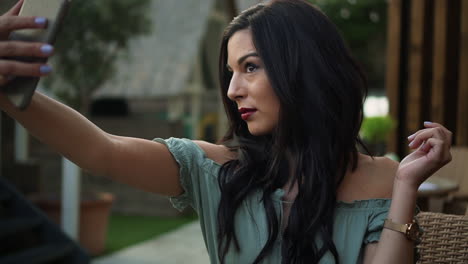 Beautiful-brunette-hispanic-model-woman-looks-at-her-phone-and-takes-selfies-in-a-casual-outfit-at-sunset-in-London