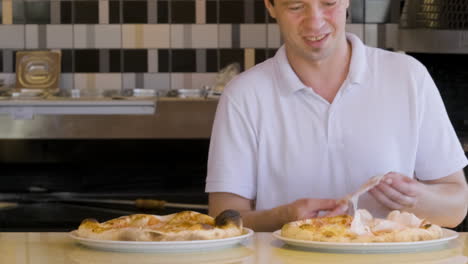 happy chef adding cured meat on pizza at restaurant