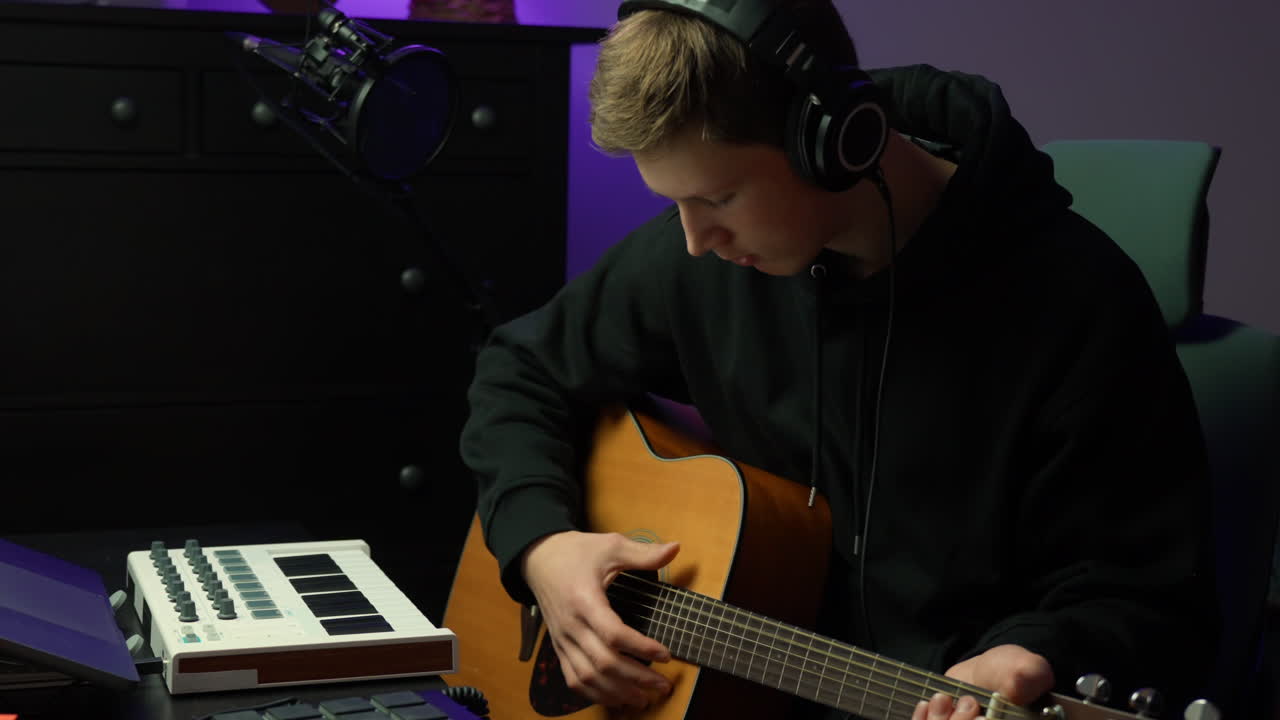 Young musician in studio, playing guitar, relaxed creative mood
