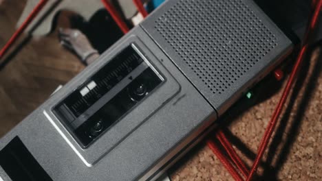 la grabadora de cassette está en la tabla de investigación, con las pruebas conectadas por una cuerda roja