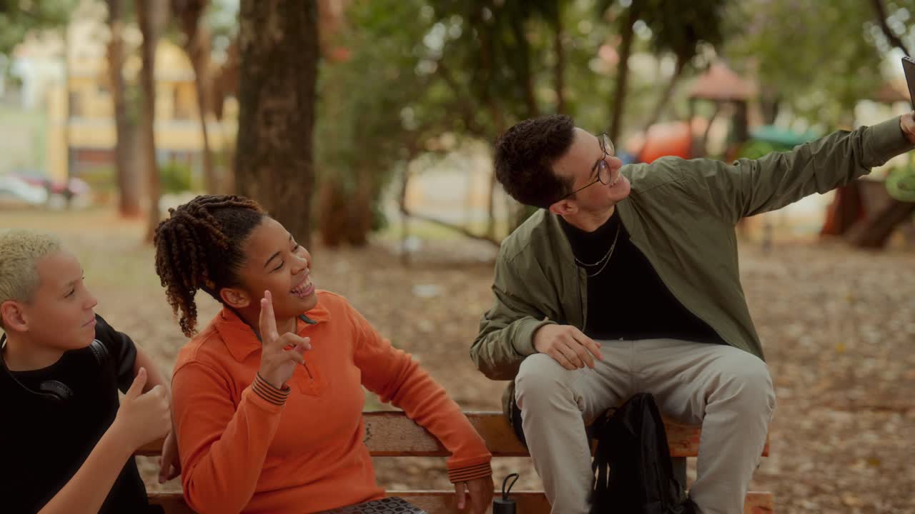 Friends interacting and using phones on a park bench