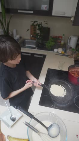 a boy cooking pancakes in a kitchen