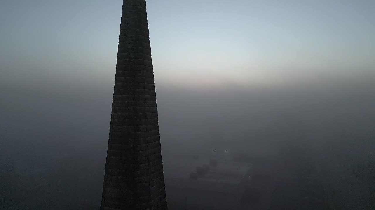 una vista aérea de una iglesia de ladrillo en primer plano, rodeada de niebla durante un amanecer dorado en long island, nueva york