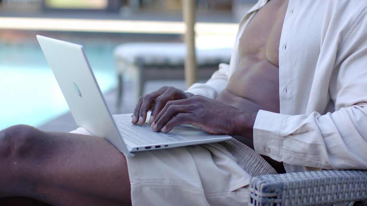 Man is starting to type as hands are touching keyboard, working on laptop at poolside