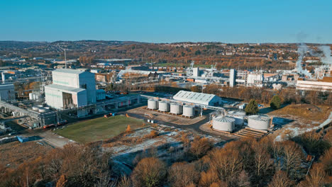 aerial footage moving towards a large industrial chemical plant, showing pipelines, metal structures, cooling towers and chemical storage