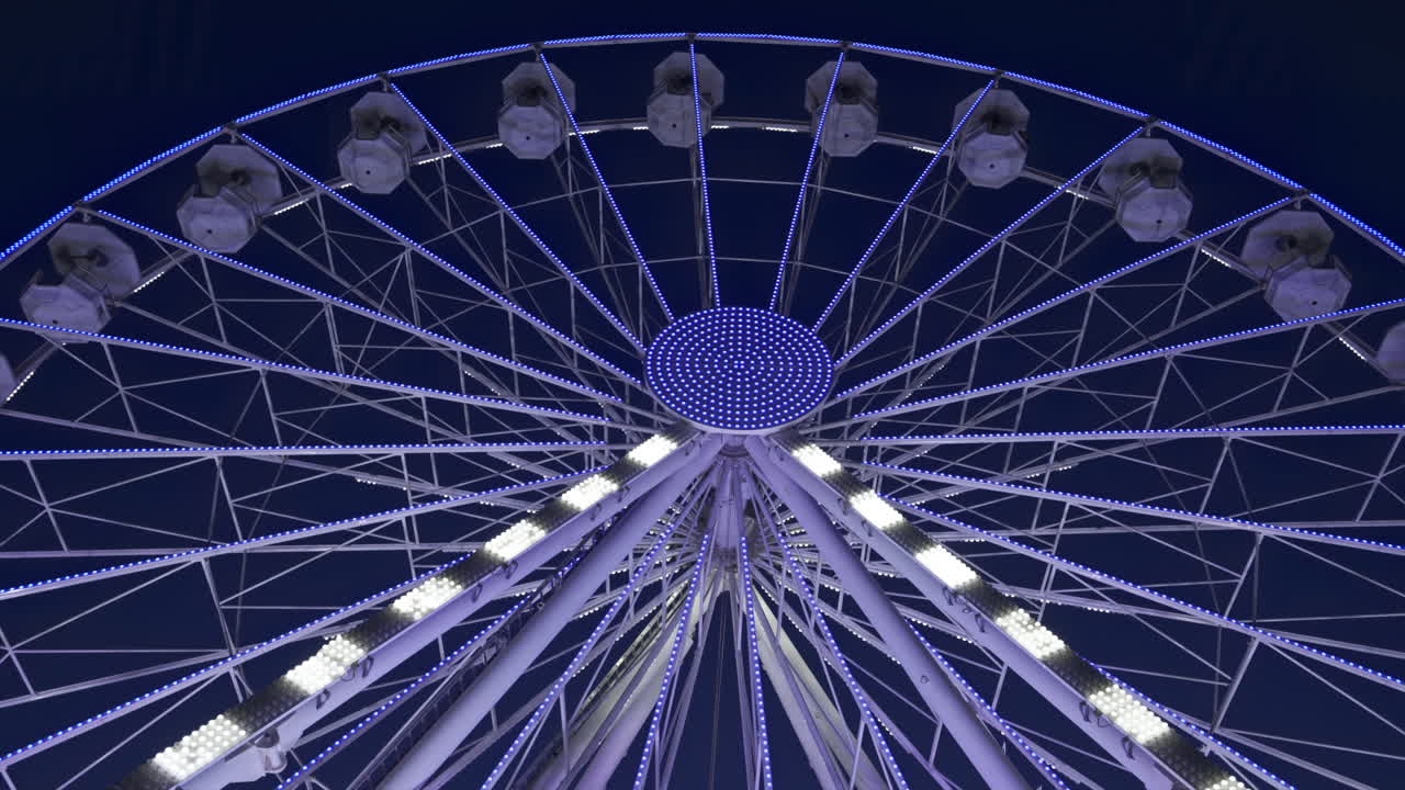 View of white, illuminated ferris wheel rotating in Antibes, France in the evening