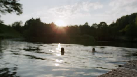 static view of two friends chilling on lake in blurry background at sunset