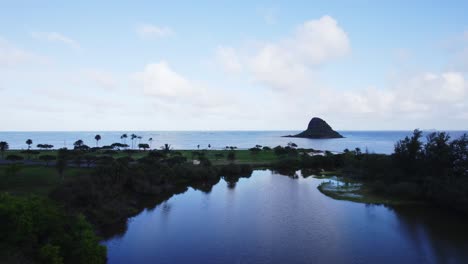 a stunning aerial view of oahu’s serene waters, featuring a peaceful pond reflecting the sky, lush greenery, and the iconic mokoli'i island in the distance