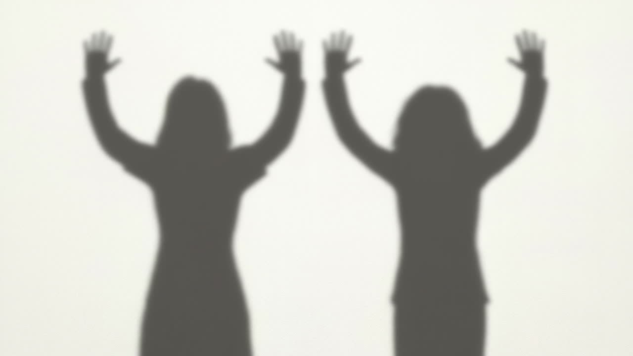 Silhouettes of Two People Raising Arms in Celebration