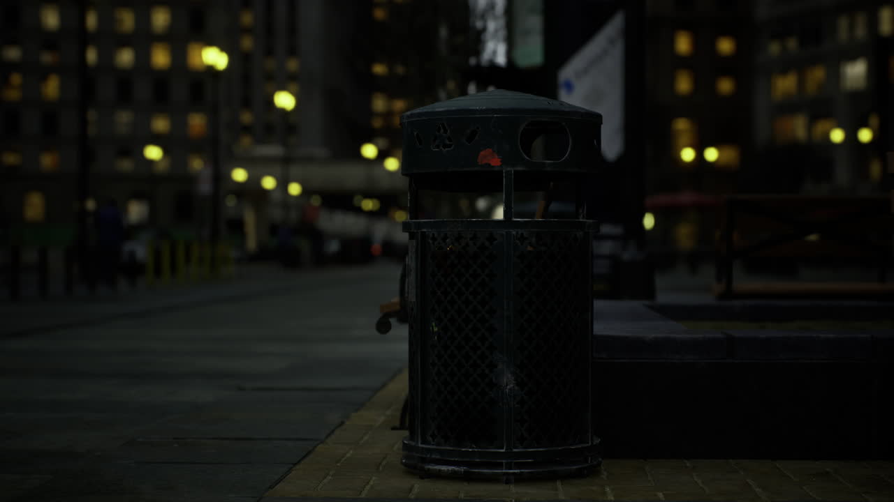Trash bin illuminated by street lights in urban city after dark