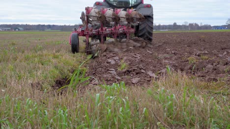 back view of farm tractor plowing land