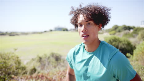 a young biracial person is outdoors, greenery in background, with copy space