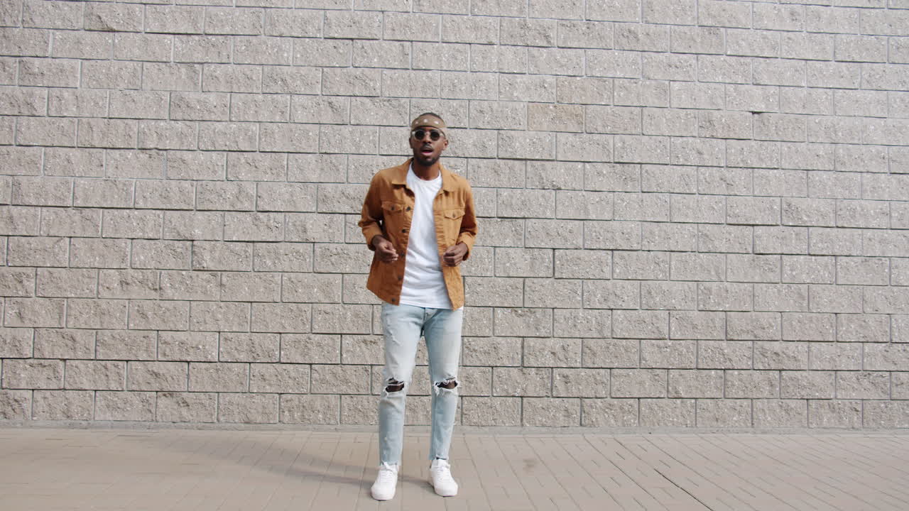 hombre elegante posando frente a una pared de ladrillo