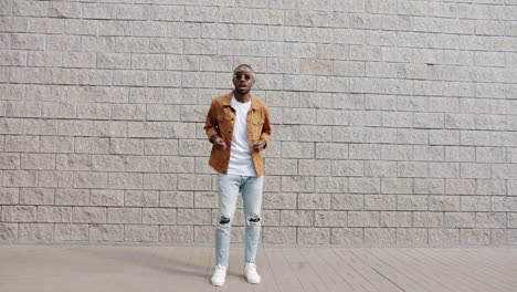 stylish man posing in front of a brick wall