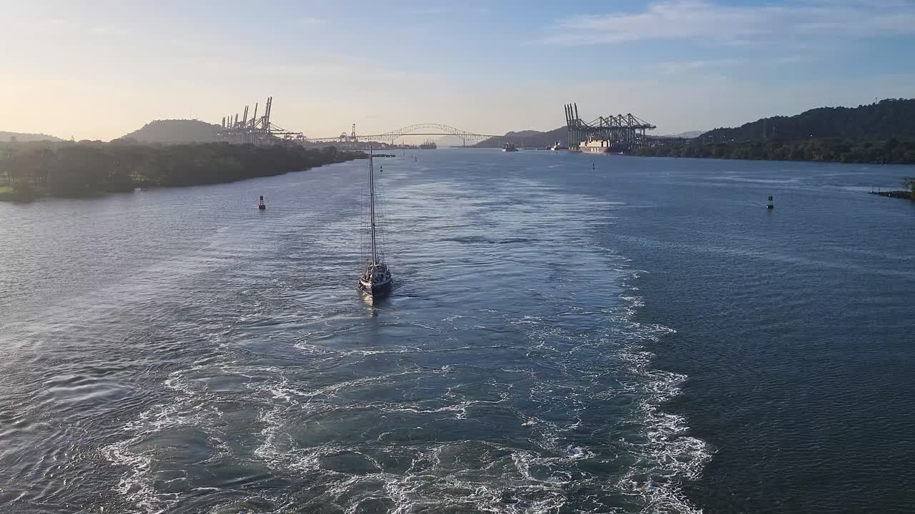 Sailboat navigating the Panama Canal with iconic Bridge of the Americas in the distance