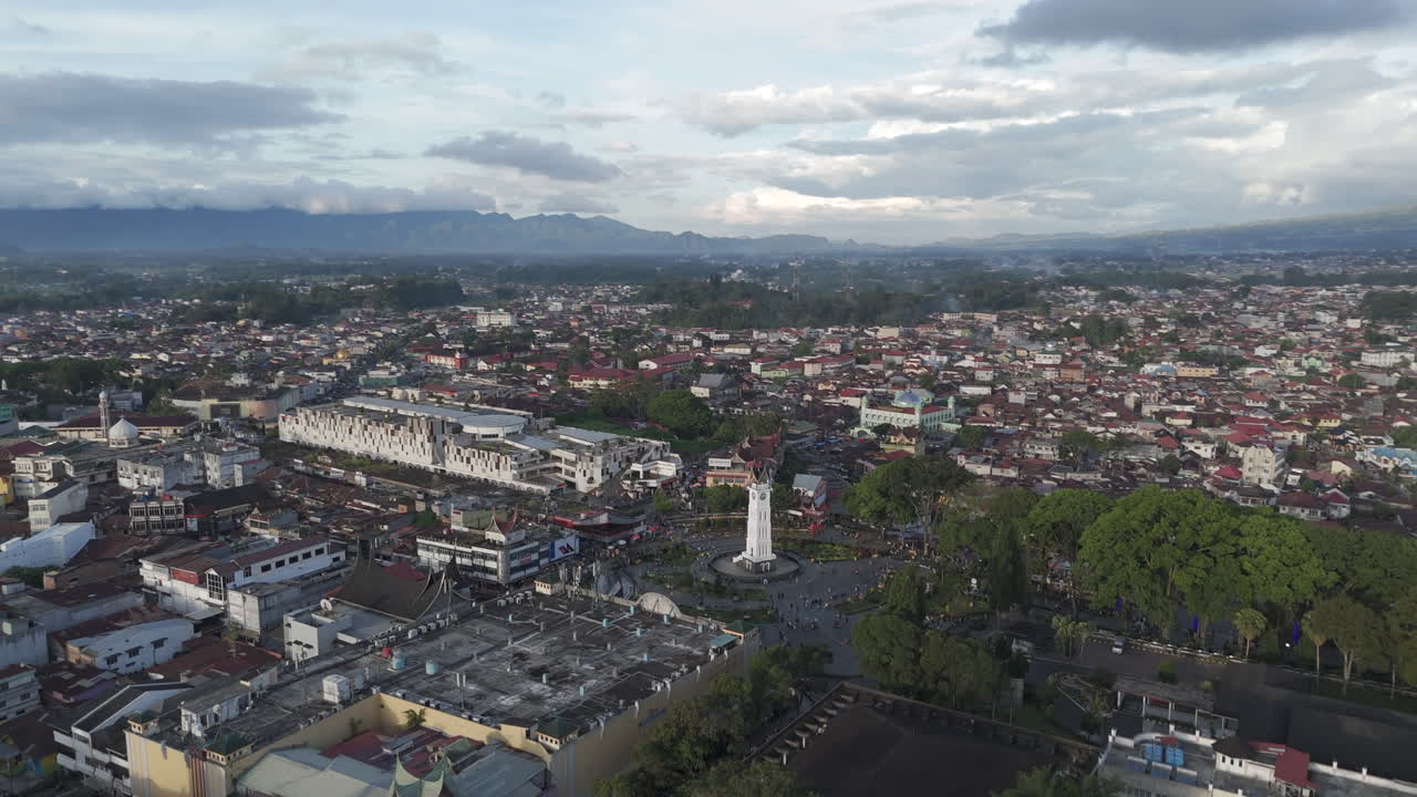 Ampia ripresa aerea con drone sulla vivace piazza del centro di Bukittinggi, Sumatra Occidentale, con l'iconico monumento della torre dell'orologio Jam Gadang, l'area del mercato e la fitta città circostante