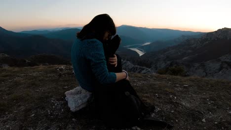 Girl-cudling-black-labrador-dog-on-a-mountain