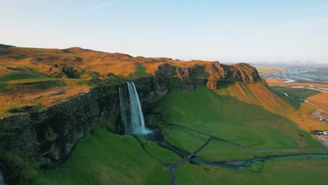 A-seagull-attacks-a-drone-flying-past-the-Seljalandsfoss-waterfall,-Iceland