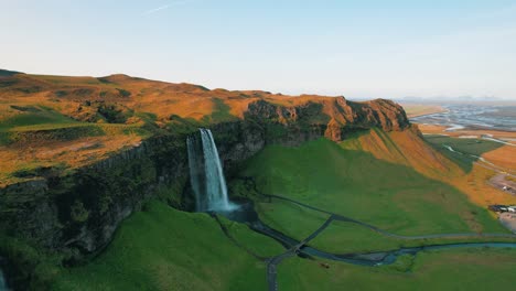 una gaviota ataca un avión no tripulado que vuela más allá de la cascada de seljalandsfoss, islandia