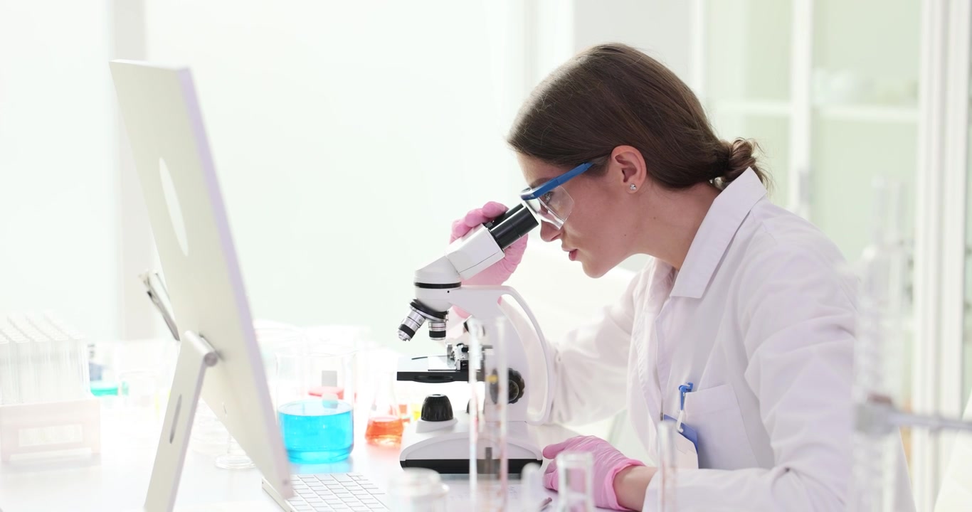 Lab researcher examines biological samples with microscope