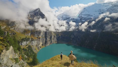 couple reaching postcard like landscape with blue lake and steep mountains