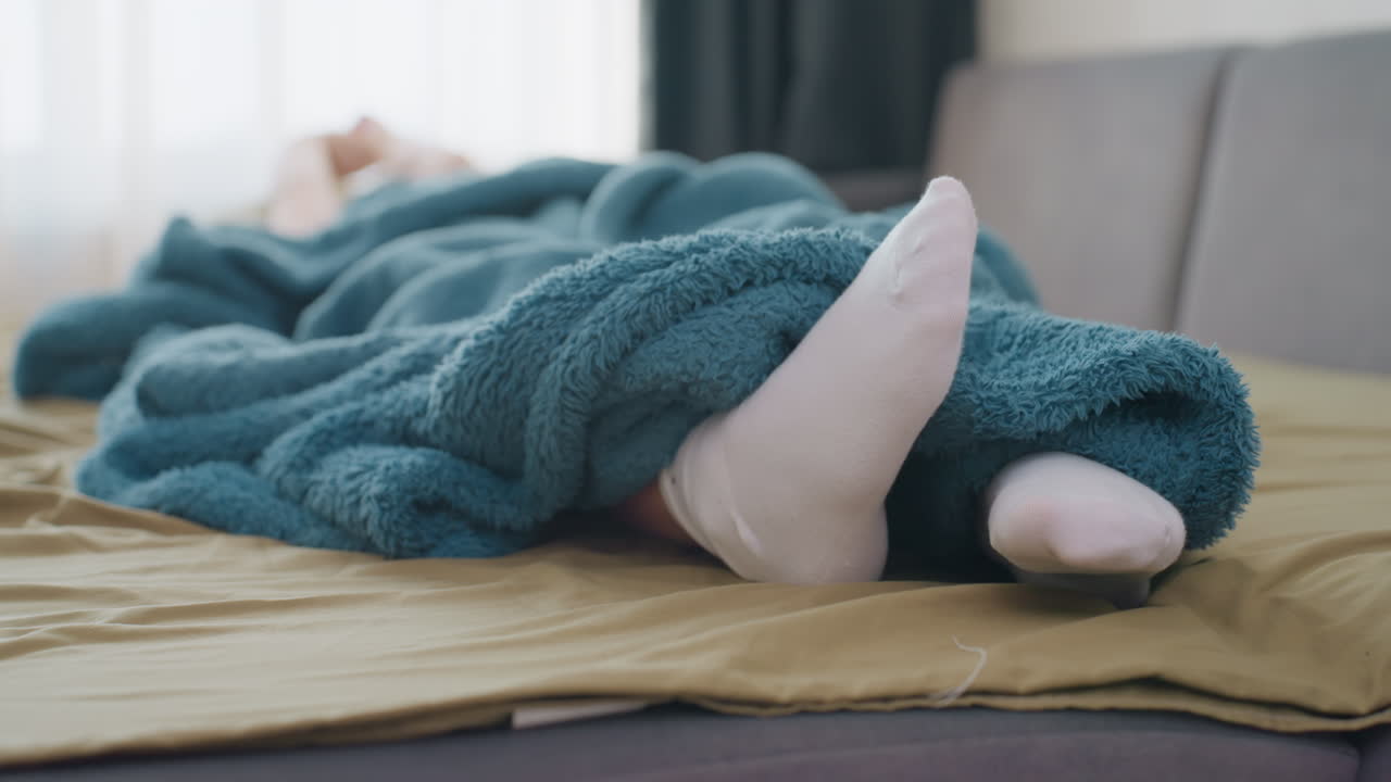 Youthful Girl In Warm Surroundings, Comfortable Young Woman Resting Beneath Colorful Blanket Sunlight, Serene Scene Of Girl Relaxed Under Vibrant Cover With Sunlight Streaming Through Curtains