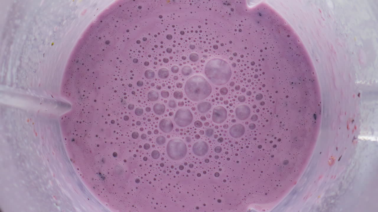 Mixed berry smoothie blender bowl close up top view. Organic milkshake preparing